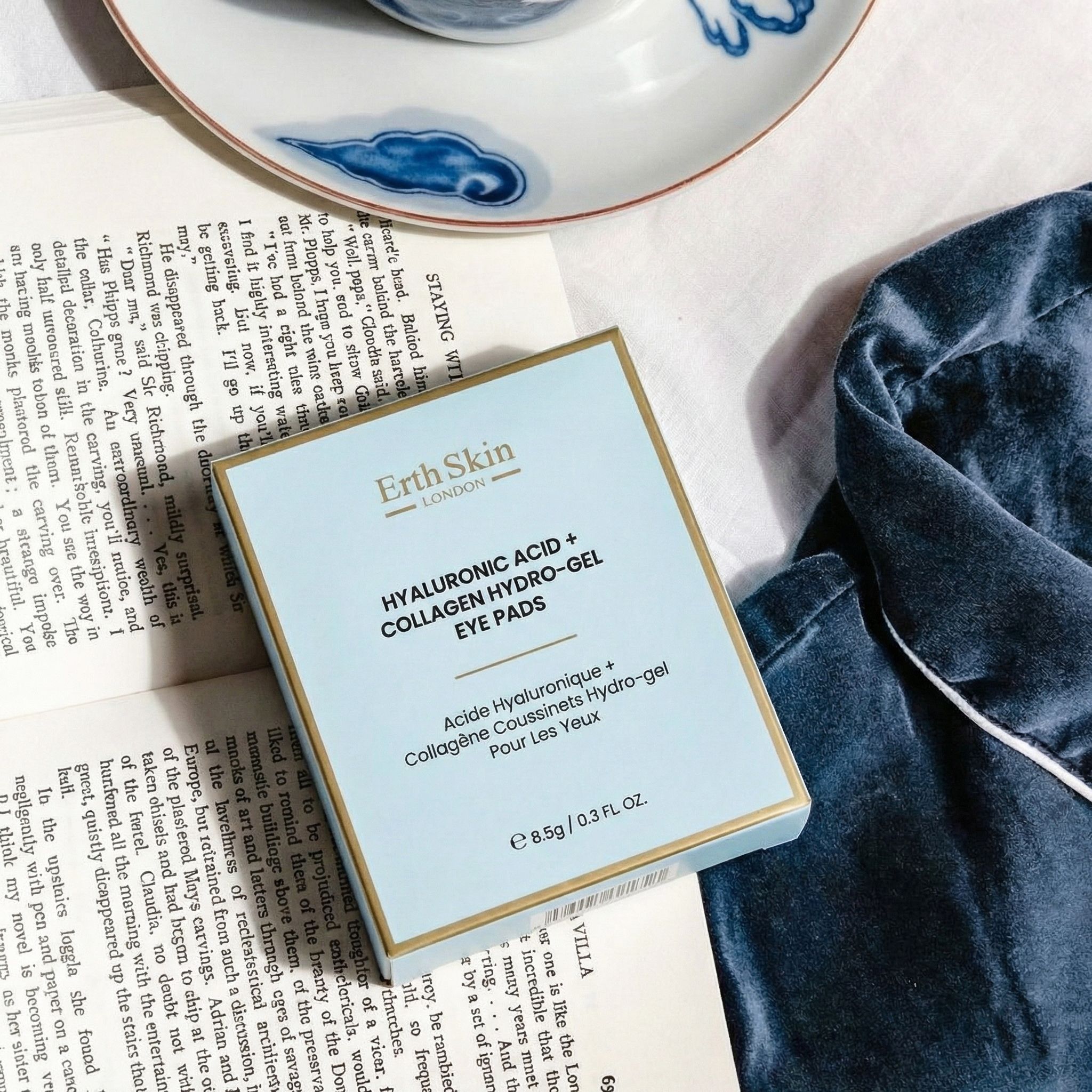 Verpakking van ErthSkin London Hyaluronic Acid + Collagen Hydrogel Eye Pads, liggend op een boek.
