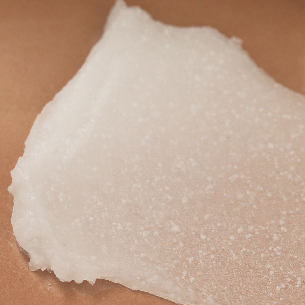 Close-up van een witte, gelachtige substantie. Textuur met kleine deeltjes. Op een lichte achtergrond.