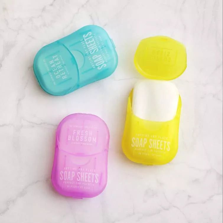 Trois étuis de savon colorés : bleu, jaune et rose. Inscription "Soap Sheets". Étui jaune ouvert avec savon.