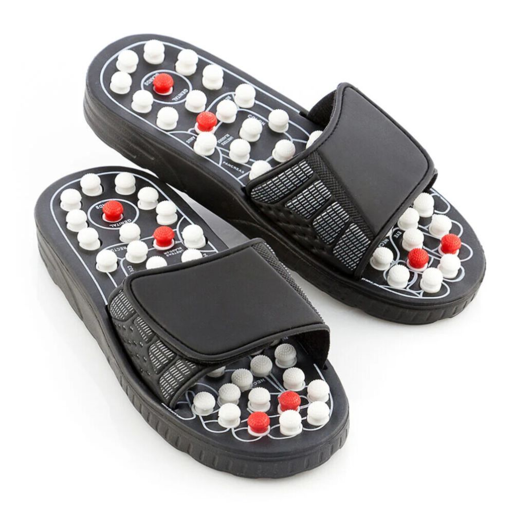 Zwarte acupressuurschoenen met witte en rode noppen. Verstelbare riem. Bovenkant met noppenpatroon.
