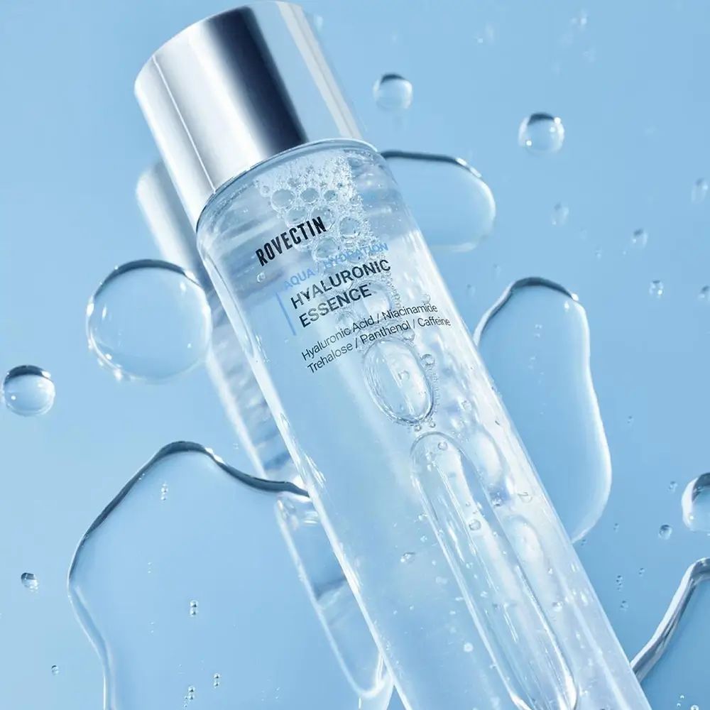 Cilindrische fles met zilveren dop, omringd door water. Opschrift: ROVECTIN Aqua/Hydration Hyaluronic Essence.