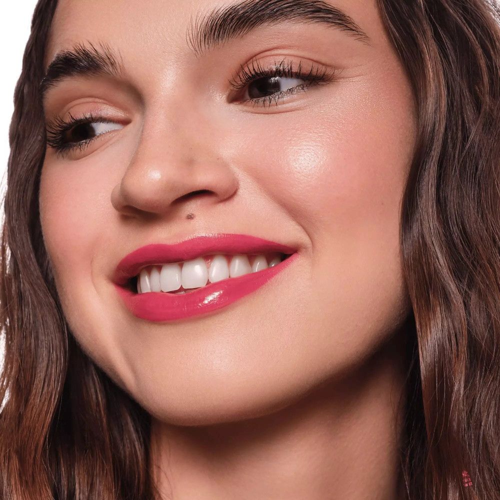 Portrait d'une femme avec des lèvres roses. Elle sourit et regarde de côté. Rouge à lèvres brillant.