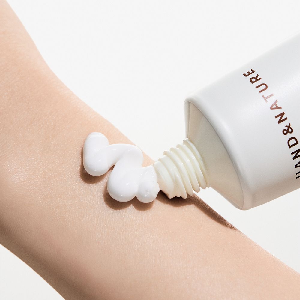 Crème pour les mains appliquée sur une main à partir d'un tube. La crème est blanche.