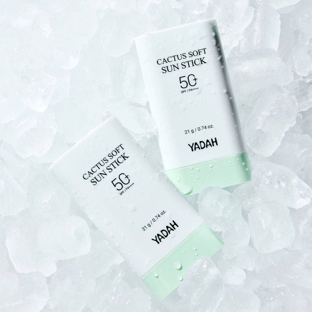 Twee witte zonnebrandsticks met groene dop, met opschrift 'Cactus Soft Sun Stick 50 SPF'.