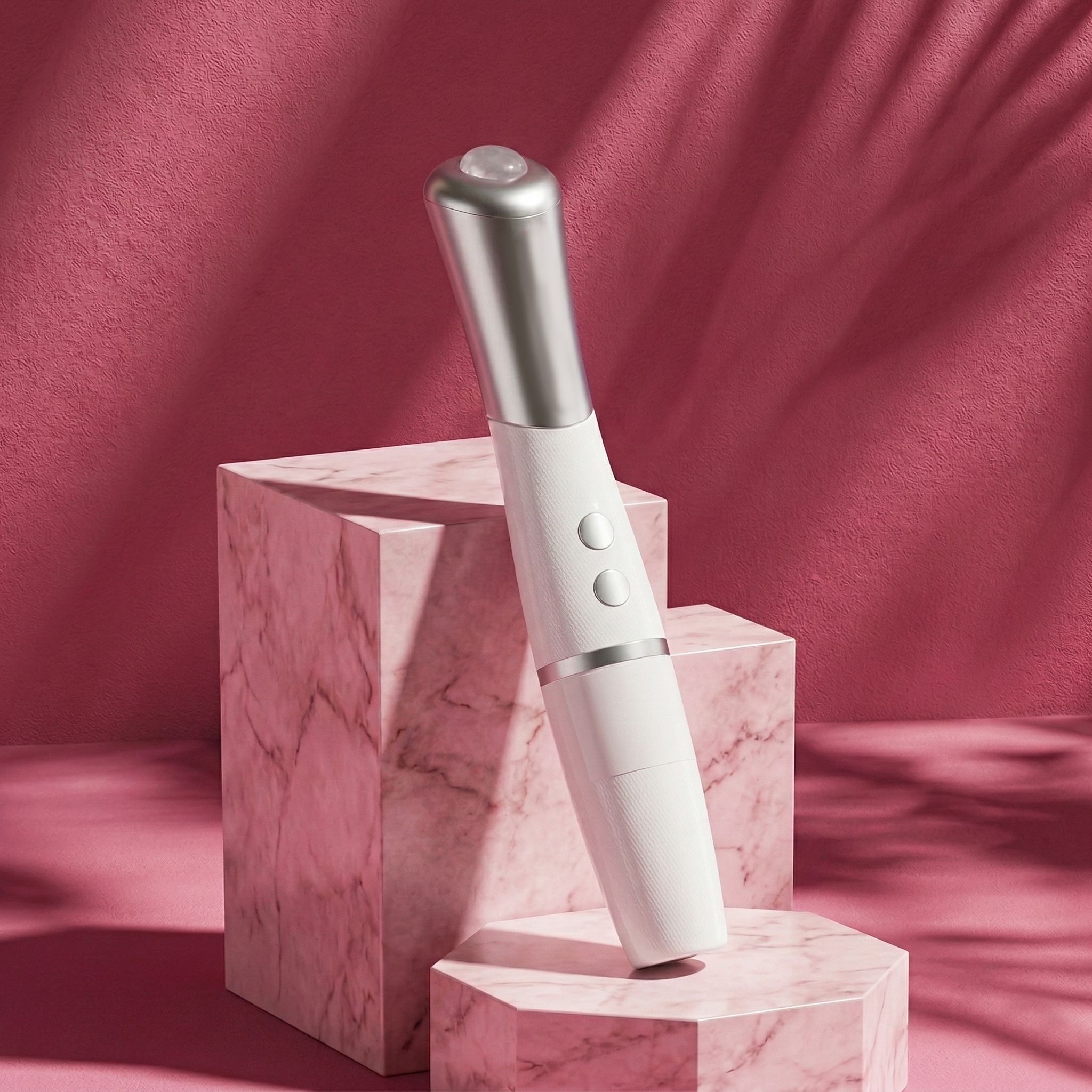 Een witte oogmassager met zilveren kop, geplaatst op een marmeren blok.