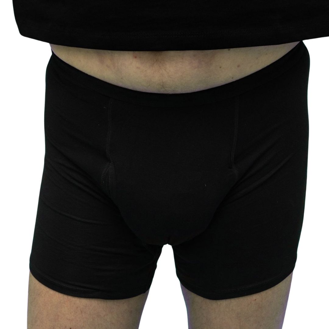 Gros plan d'un homme en boxer noir. Zone abdominale visible, taille élastique.