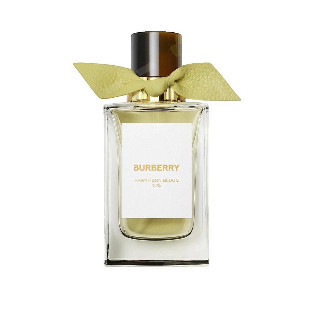 Flacon de parfum avec ruban jaune. Forme rectangulaire, bouchon doré, étiquette blanche avec texte.