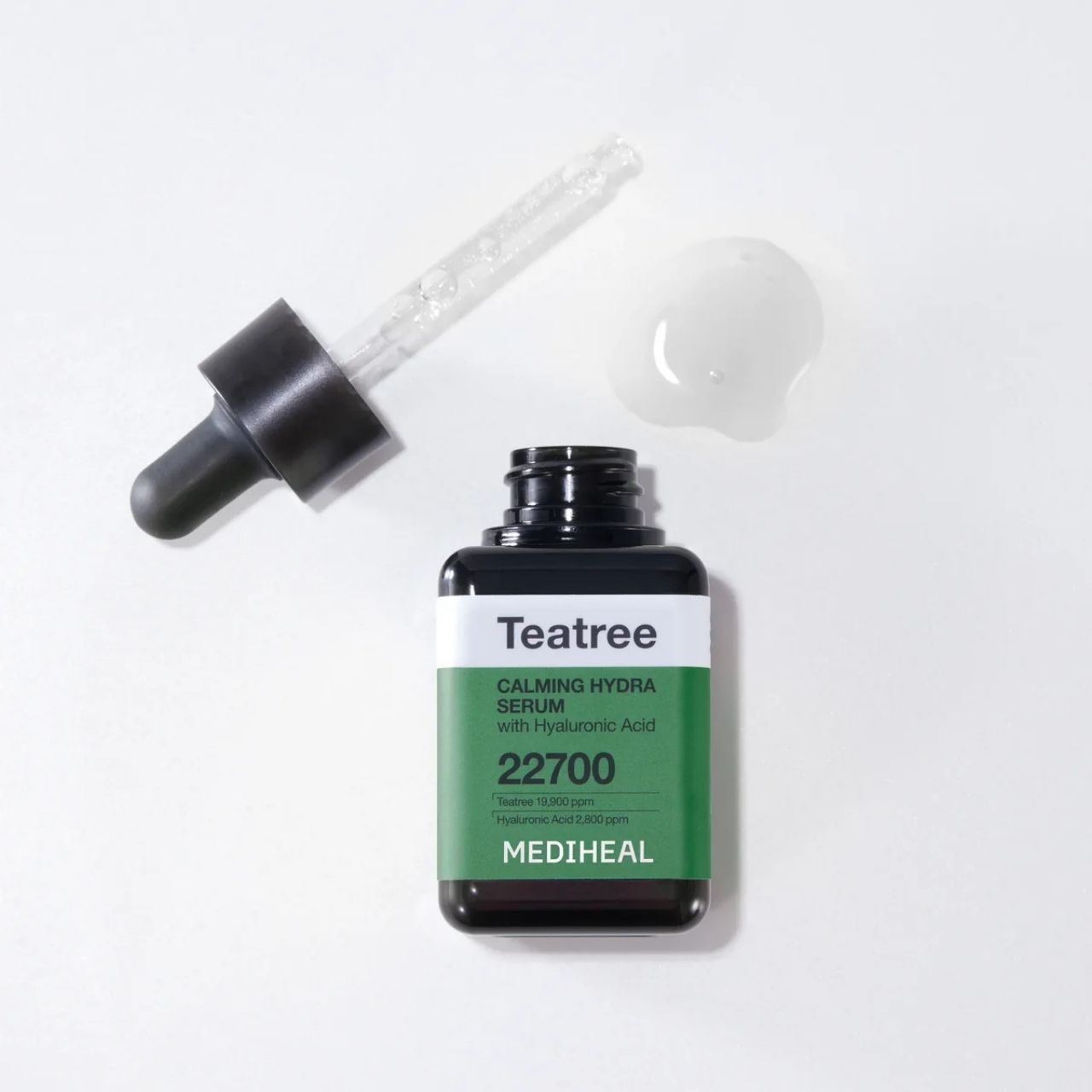 Flacon de sérum hydratant apaisant à l'arbre à thé MEDIHEAL avec pipette et goutte de sérum à côté.