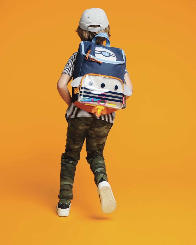 Kind draagt een donkerblauwe rugzak met een raketontwerp. De rugzak heeft vleugels en een transparante voorzak.