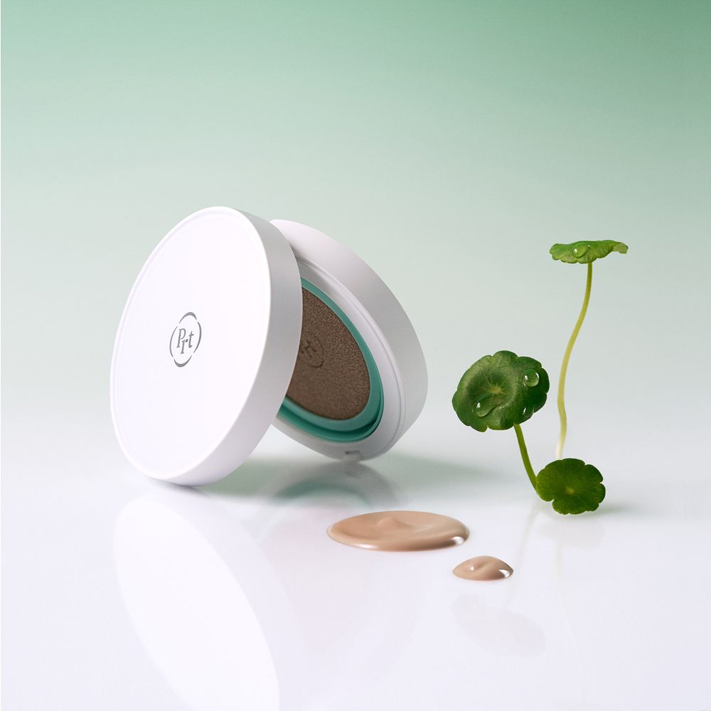 Open PURITO Centella BB Cushion-verpakking met product en druppels ernaast. Plant op de achtergrond.