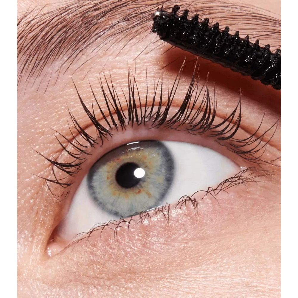 Oog met wimpers. Wimpers bedekt met gel. Zwarte borstel in gebruik. Cosmetisch product.