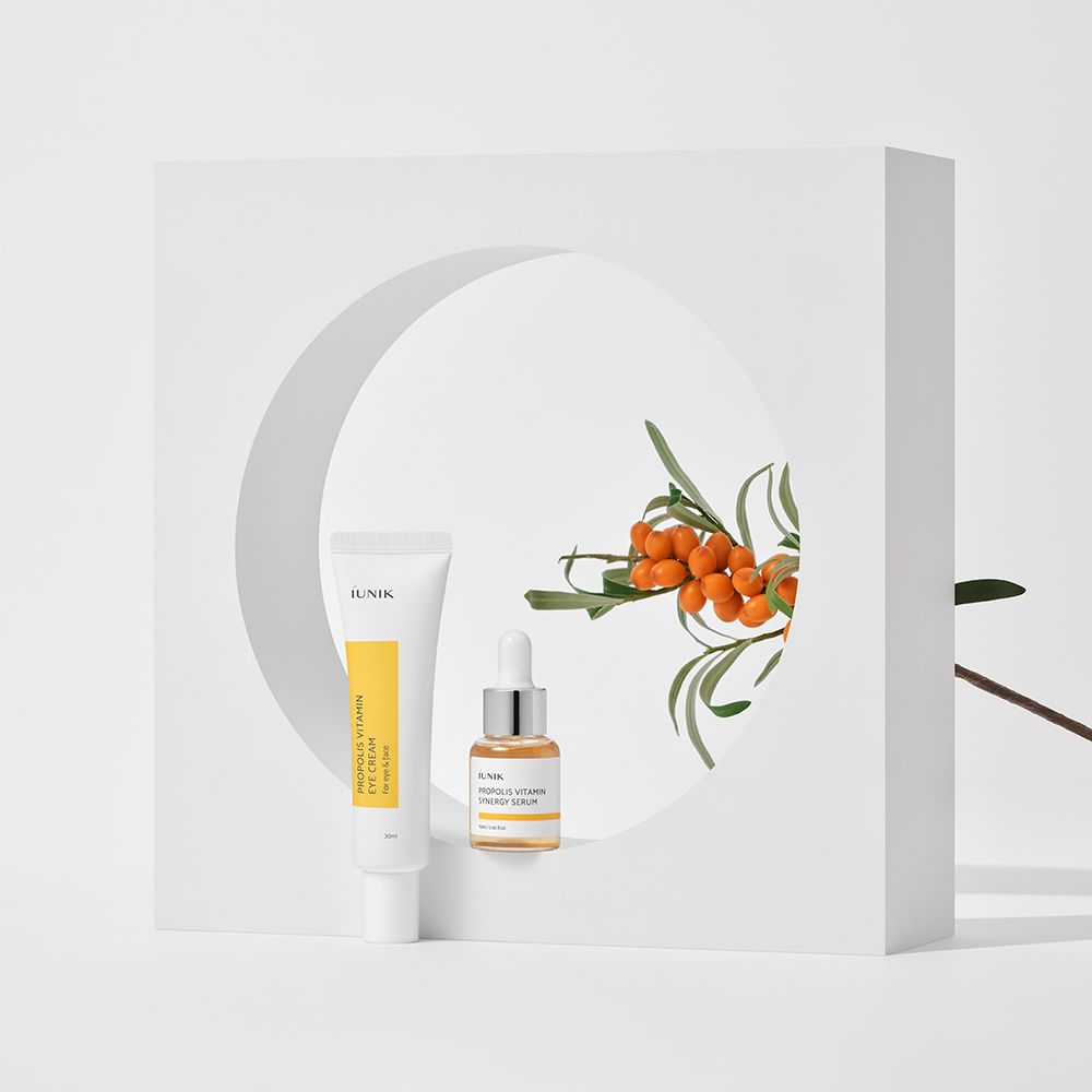 iUNIK Propolis Vitamin Eye Cream Set. Tube en serumfles op witte achtergrond. Oranje bessen.