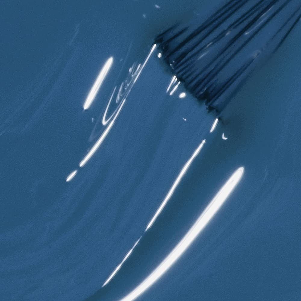 Pinceau de vernis à ongles dans du vernis bleu. Gros plan, surface brillante.