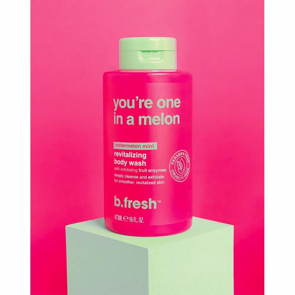 Roze douchegelfles met groene dop op een sokkel. Tekst: "you're one in a melon", "revitalizing body wash", "b.fresh".