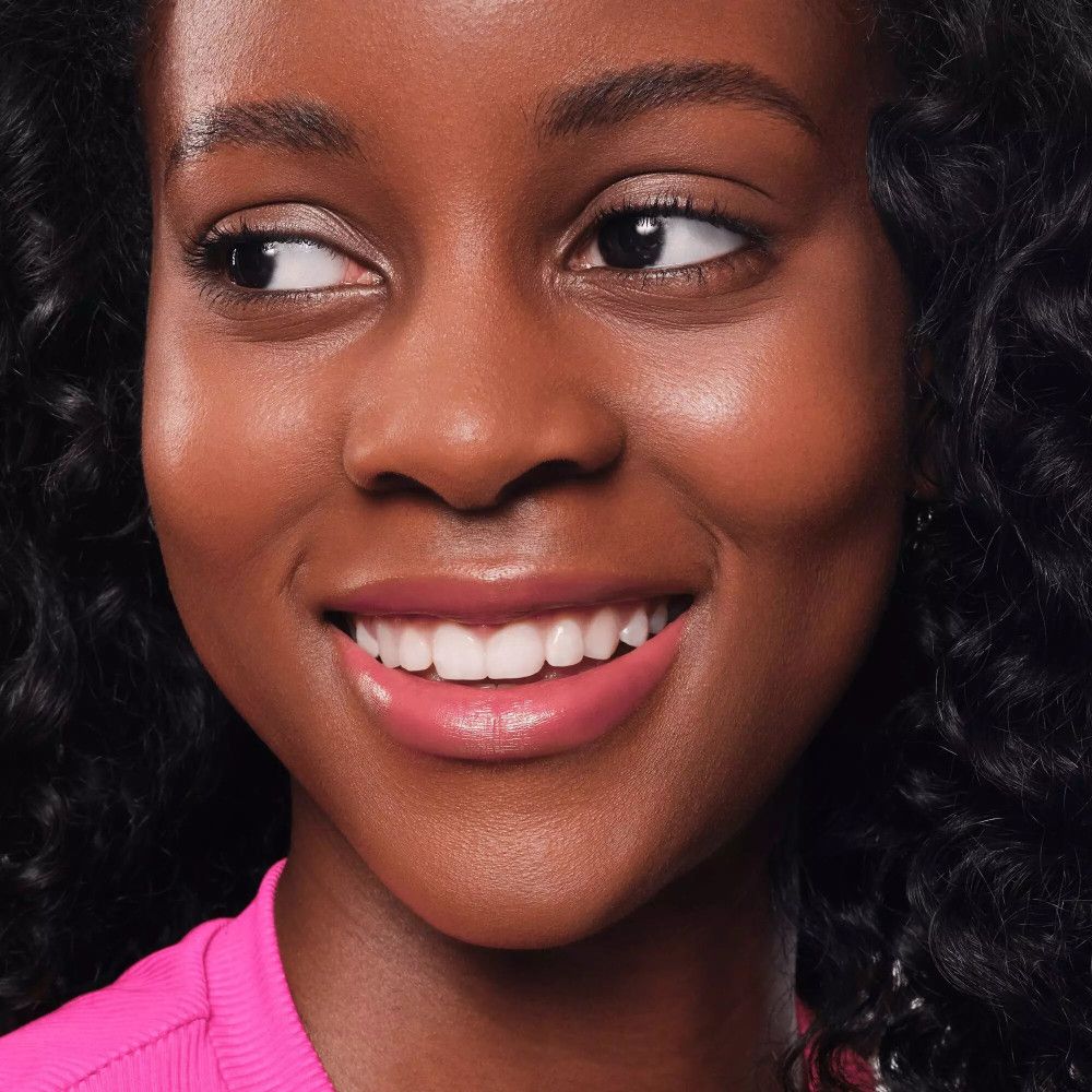 Portrait d'une femme avec des lèvres roses. Elle sourit et regarde de côté. Rouge à lèvres brillant.