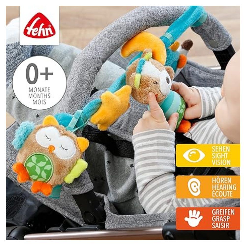 Chaîne de poussette avec animaux en peluche. Bébé touche les jouets. Marque 'fehn' et recommandation d'âge '0+ mois' visibles.