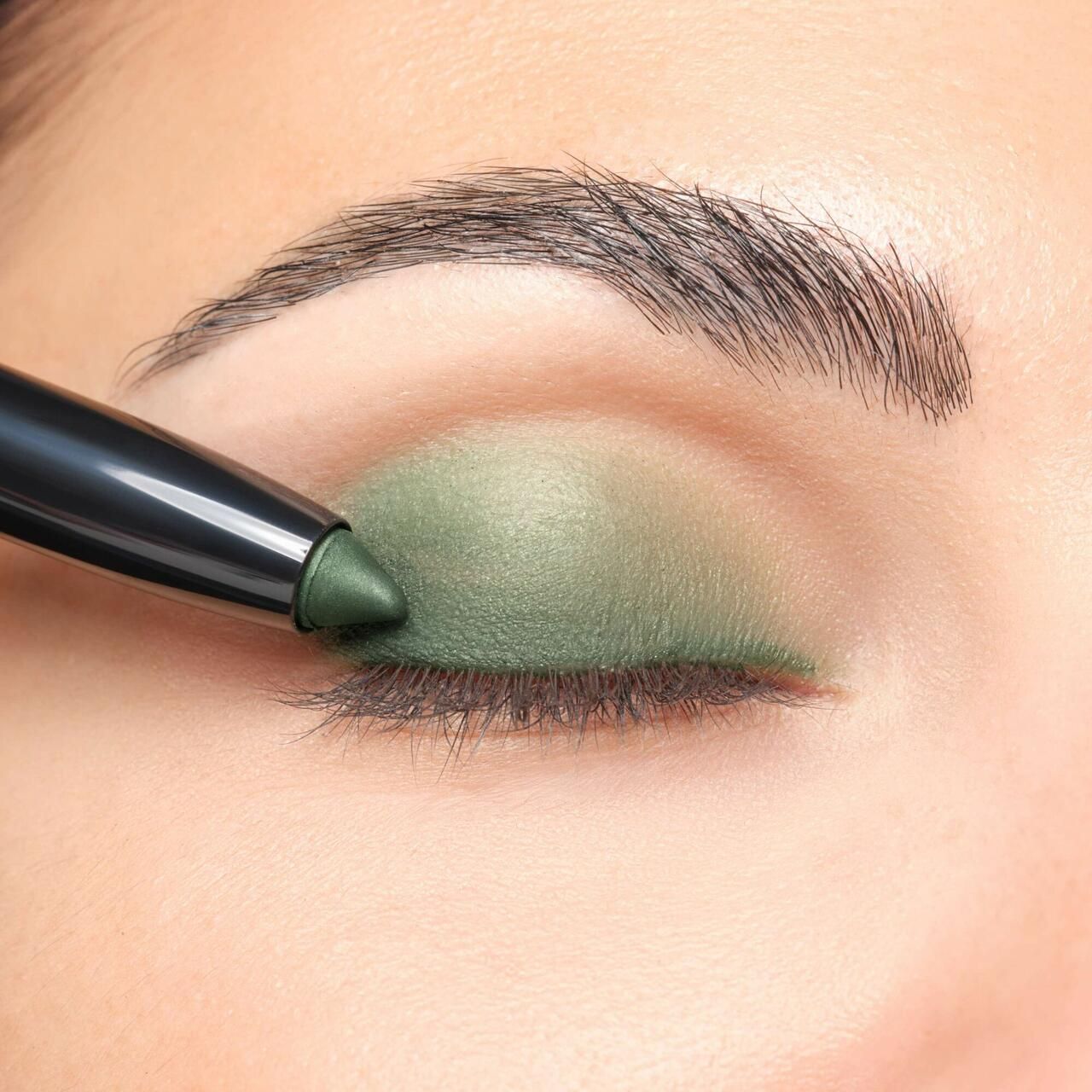 Artdeco High Performance Eyeshadow Stylo aangebracht op ooglid. Groene oogschaduw. Zwarte stift.