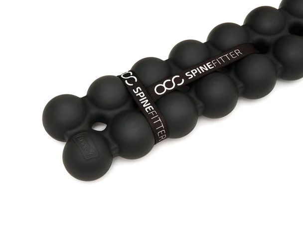 Close-up van een zwarte SISSEL Spinefitter. Ronde elementen, verbonden door een band met SPINEFITTER-opschrift.
