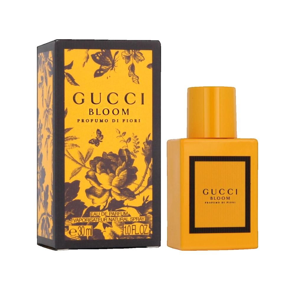 Flacon jaune à côté d'une boîte. Inscription: Gucci Bloom Profumo di Fiori. Boîte à motifs floraux.