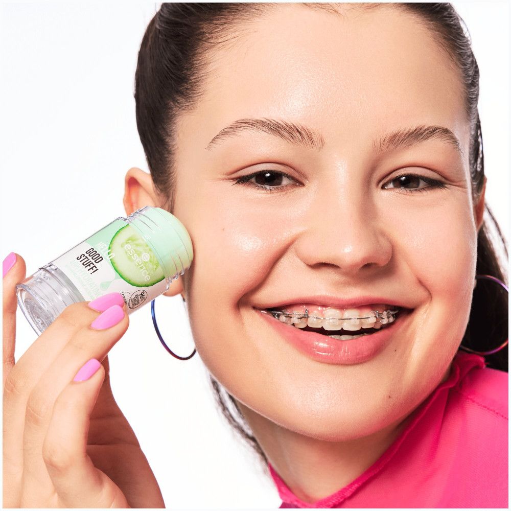 Jeune femme appliquant un stick de sérum. Produit avec motif concombre. Ongles roses vernis. Visage avec appareil dentaire.