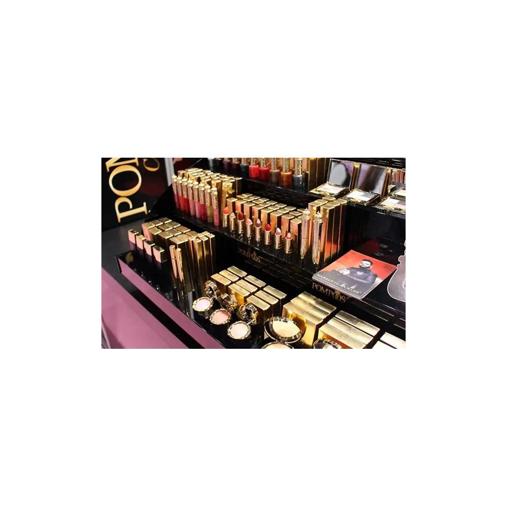 Présentoir de produits cosmétiques dorés et noirs. Produits avec le logo "POMPÖÖS".