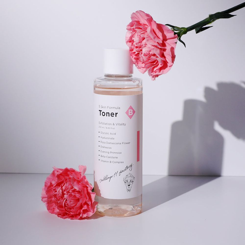Toner pour la peau avec bouchon blanc et étiquette, à côté d'œillets roses. Contient de l'acide glycolique. Marque: Village 11 Factory.