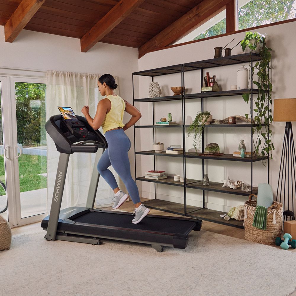 Vrouw die op een loopband rent. Zwarte loopband, grijs frame. Schwinn Fitness SFT 3.5.