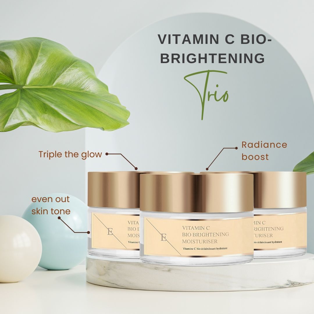 Trois pots avec couvercles dorés. Les étiquettes indiquent : Vitamin C Bio Brightening Moisturiser. Texte : Trio, Radiance boost, even out skin tone.