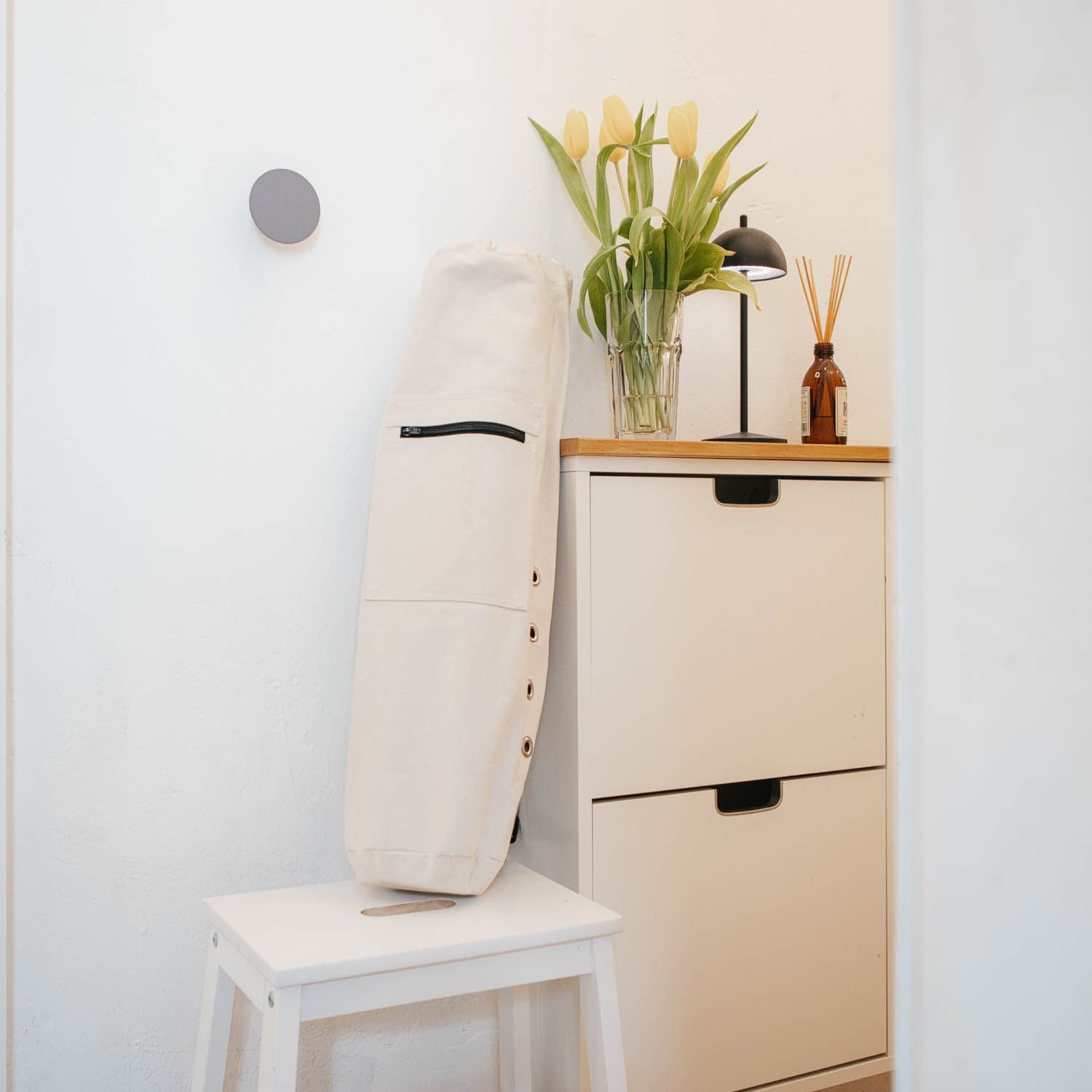 Beige yogamatten tas op een kruk. Ritssluiting, knopen en zwarte details.