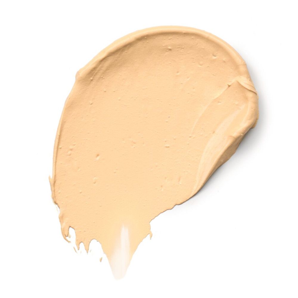 Lichte foundationtint op witte achtergrond. Romige textuur, uitgesmeerd.