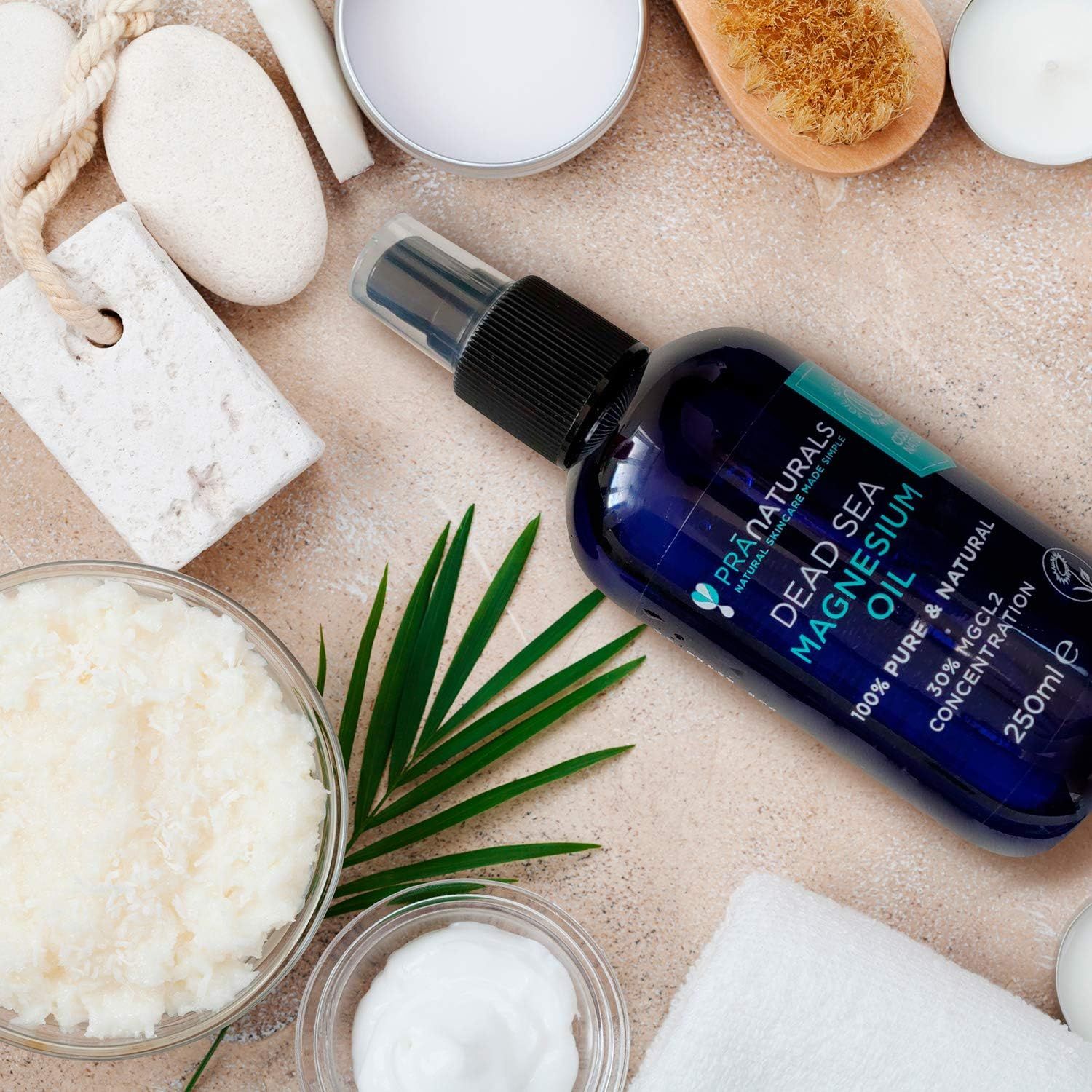 Blauwe fles met verstuiver, omringd door wellnessproducten. Tekst: Dead Sea Magnesium Oil, 100% Pure & Natural, 30% MGCL2 Concentration.