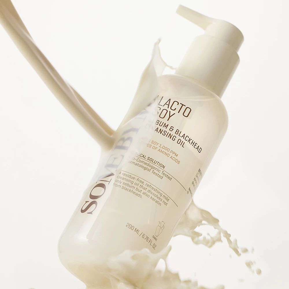Flacon avec pompe, rempli de liquide, avec éclaboussures de lait. Inscription : SOMEBYMI Lacto Soy Sebum & Blackhead Cleansing Oil. 200 ml.