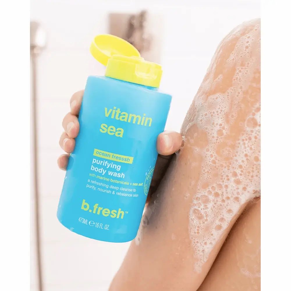 Blauw-turkoois flesje met gele dop. Opschrift: Vitamin Sea, purifying body wash, b.fresh. Flesje wordt door een hand vastgehouden.