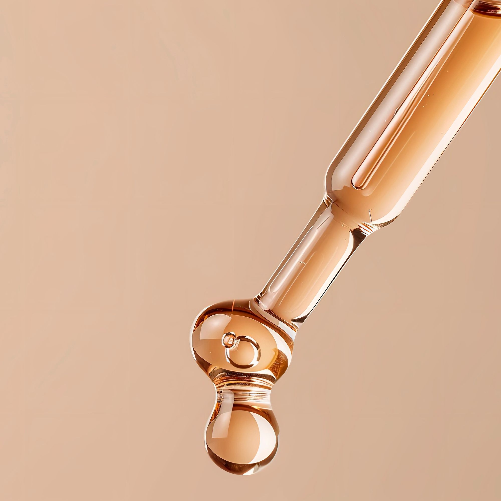 Close-up van een druppelaar met serum. Een druppel serum hangt aan het einde van de druppelaar.