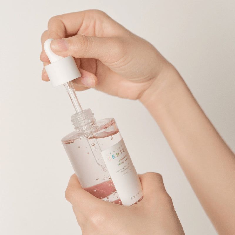 Handen houden serumfles met pipet vast. Merk: SKIN1004.