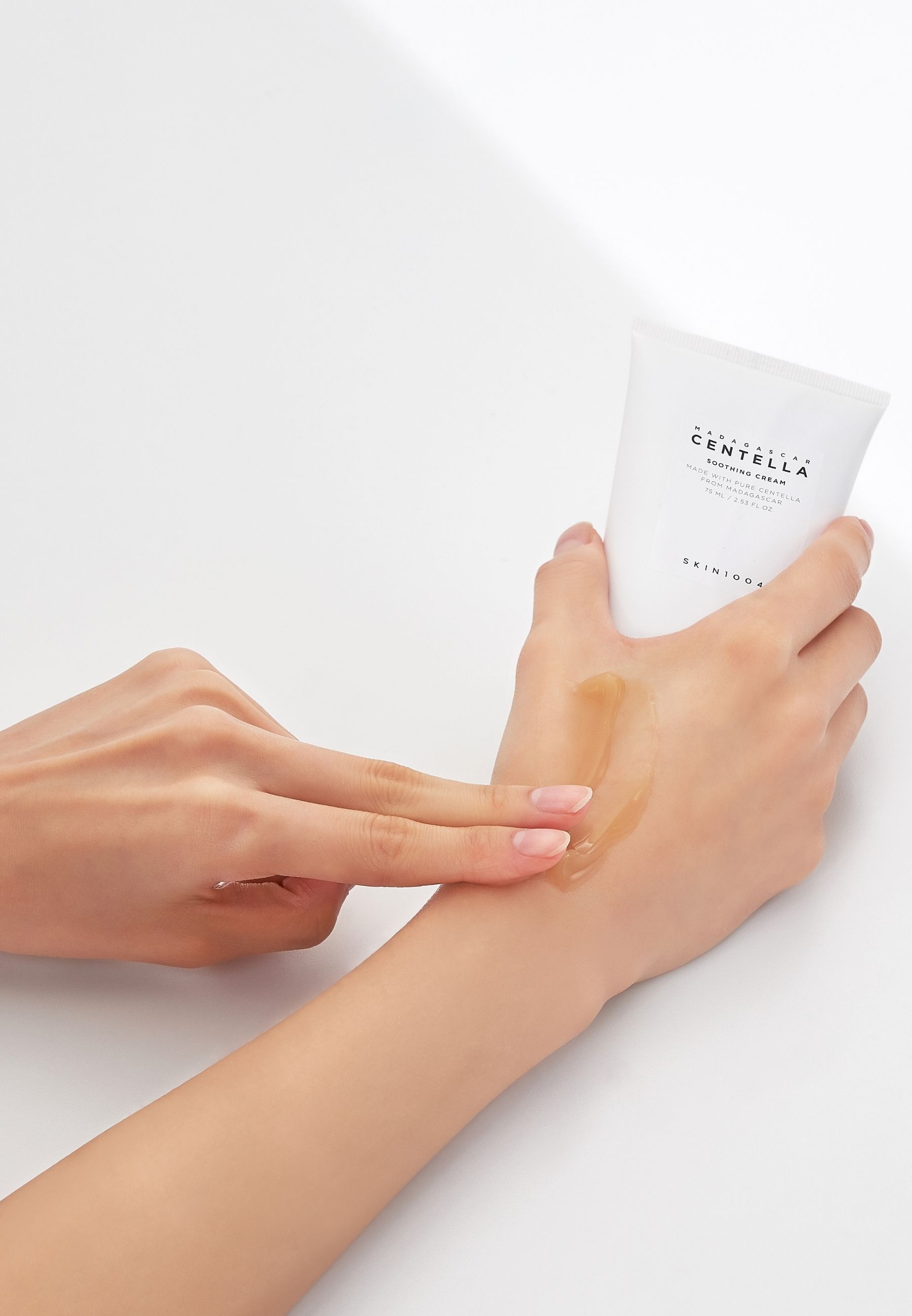 Handen houden tube vast en smeren crème. Gelige crème op de hand.