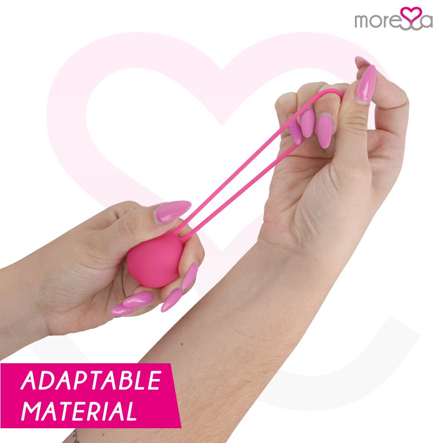 Mains tenant une balle en silicone rose avec cordon, montrant sa flexibilité.