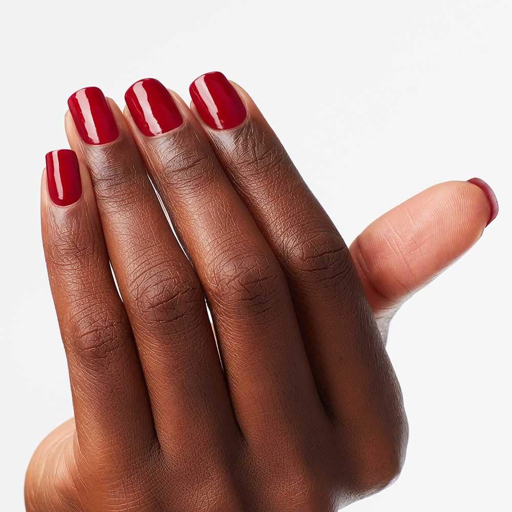 Main avec ongles vernis. Vernis à ongles rouge foncé. Sur fond clair.