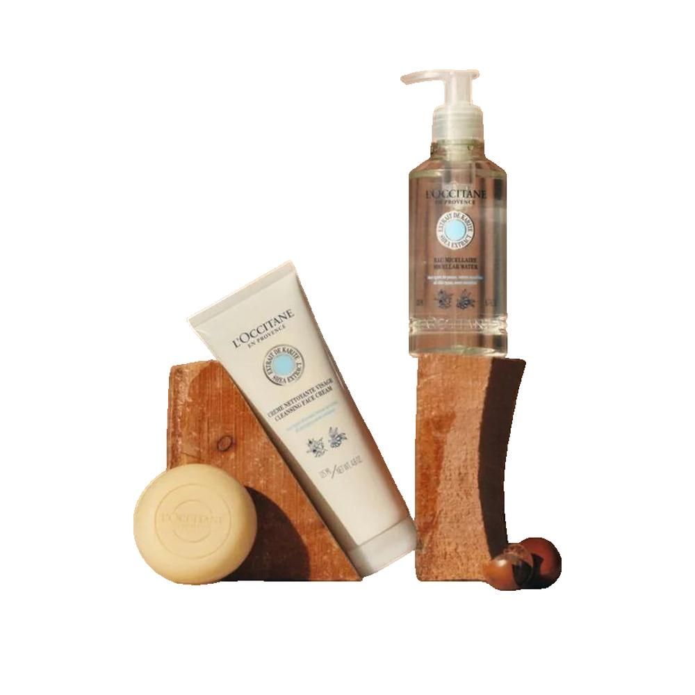 Trois produits L'Occitane : flacon d'eau micellaire, tube de crème et savon. Tous avec étiquettes et logo. Placé sur des blocs de bois.