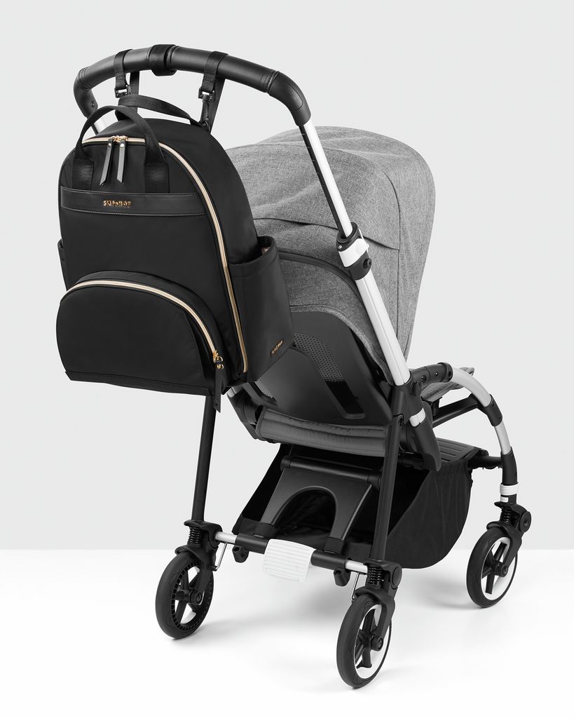 Zwarte rugzak bevestigd aan een kinderwagen. Gouden ritsen.