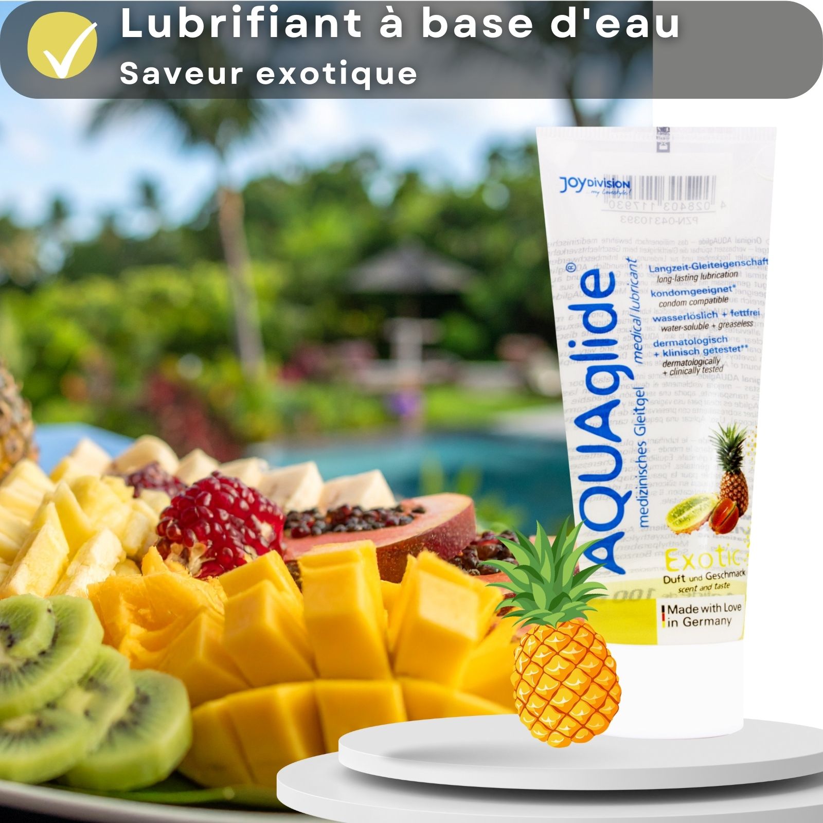 Tube de gel lubrifiant AQUAglide à côté d'un plateau de fruits. Texte : À base d'eau, saveur exotique. Avec ananas et kiwi.