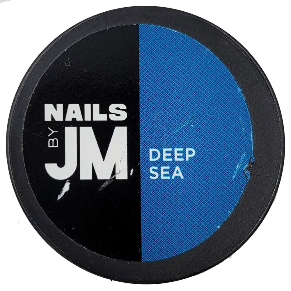 Contenant rond avec bord noir. Inscription "NAILS BY JM" et "DEEP SEA" sur fond bleu.