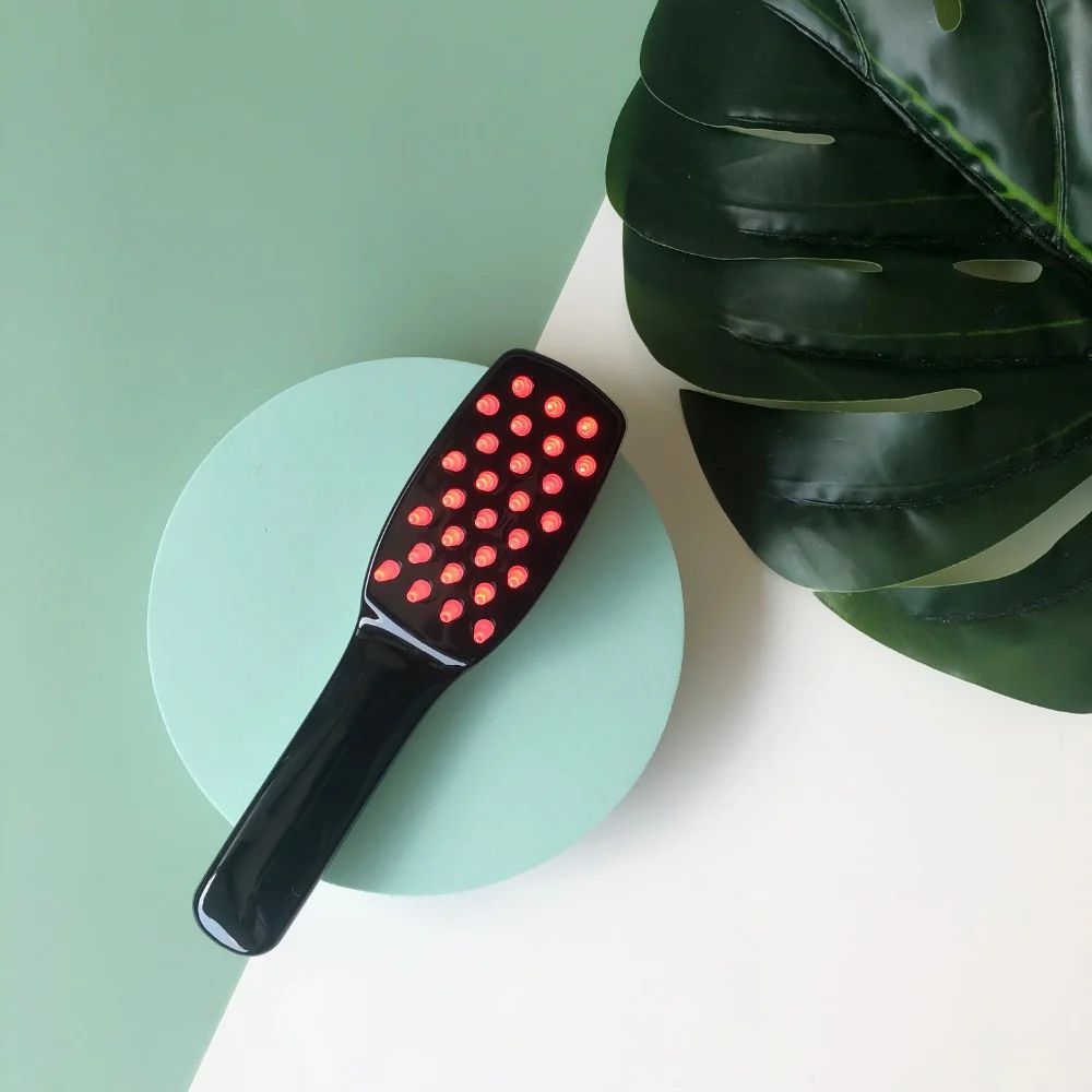 Zwarte haarborstel met veel rode LED's, liggend op een mintgroene cirkel.