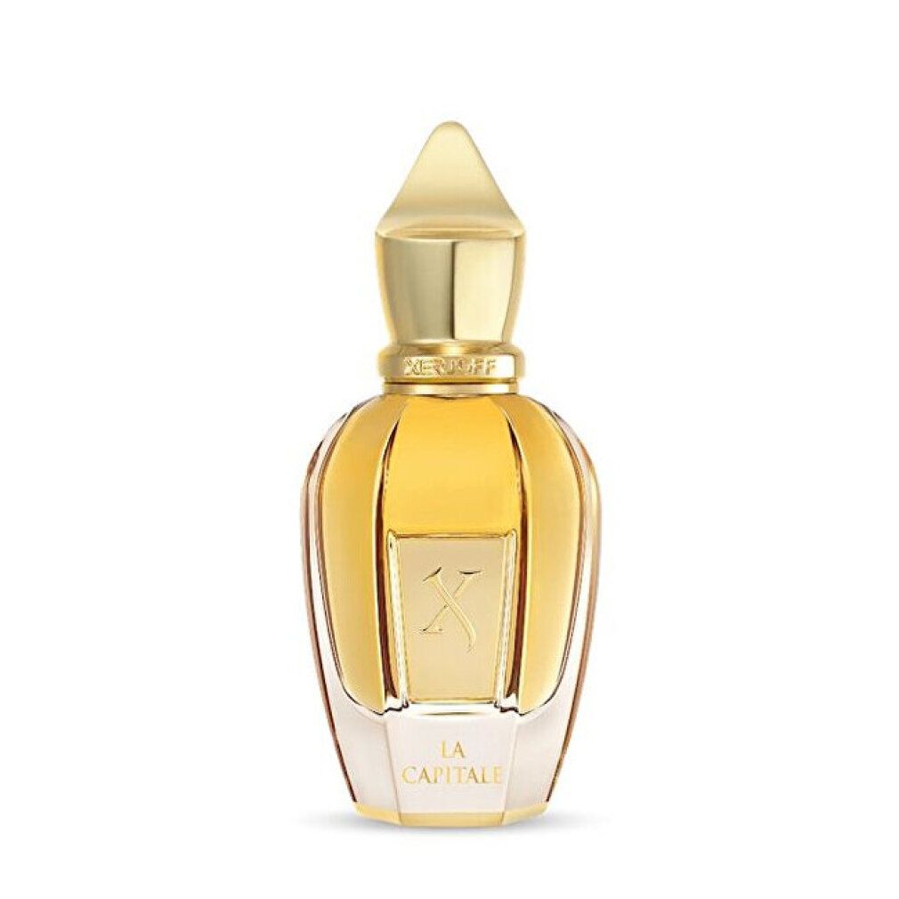 Flacon de parfum doré avec une base hexagonale et un bouchon pointu. "LA CAPITALE" et un logo "K" sont imprimés sur le devant.