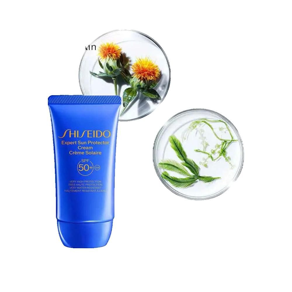 Tube bleue Shiseido Sun Expert Crème Visage SPF50, avec fleurs dans des coupelles en verre.