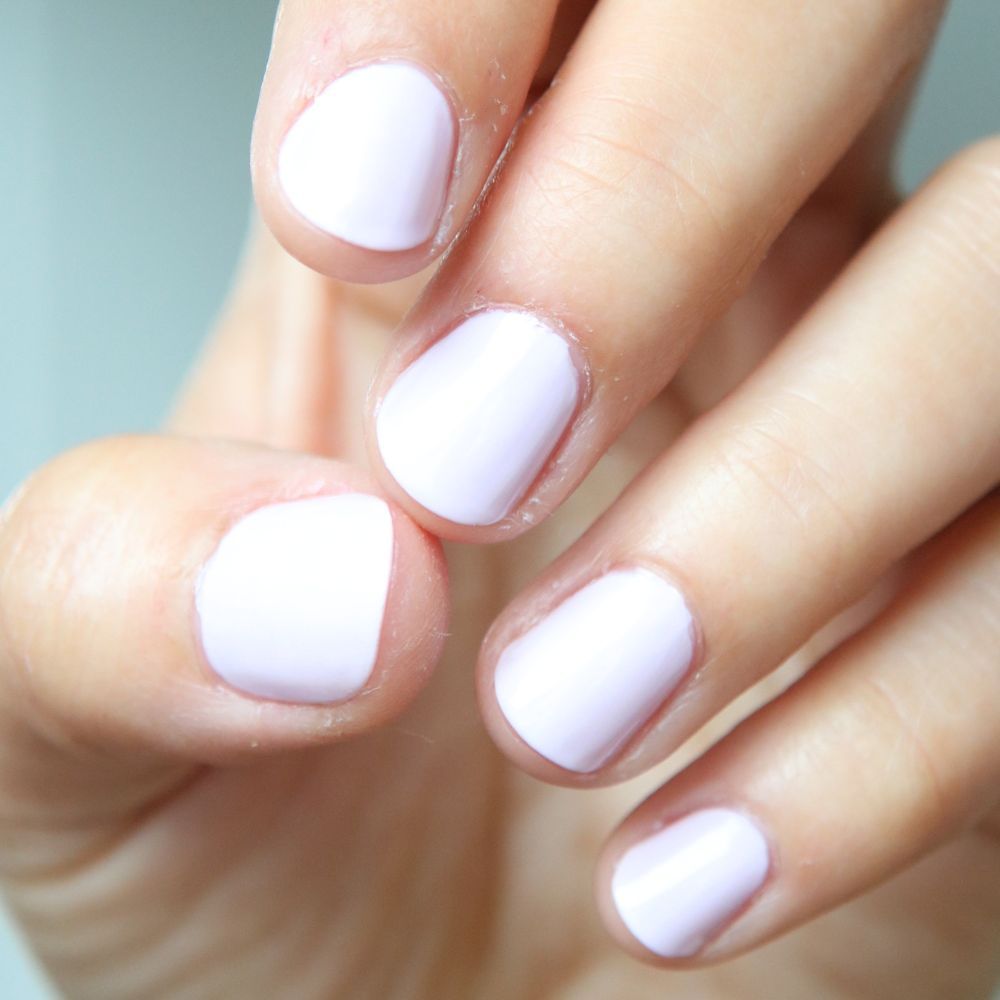 Close-up van vijf vingers met lichtpaarse nagellak. De nagels zijn kort en gelakt.