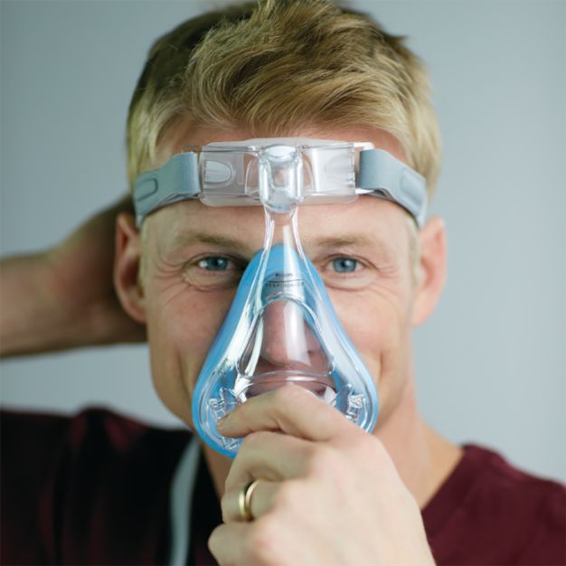 Homme avec masque CPAP Philips Amara SE Gel Full : ajustement du masque buccal et nasal.