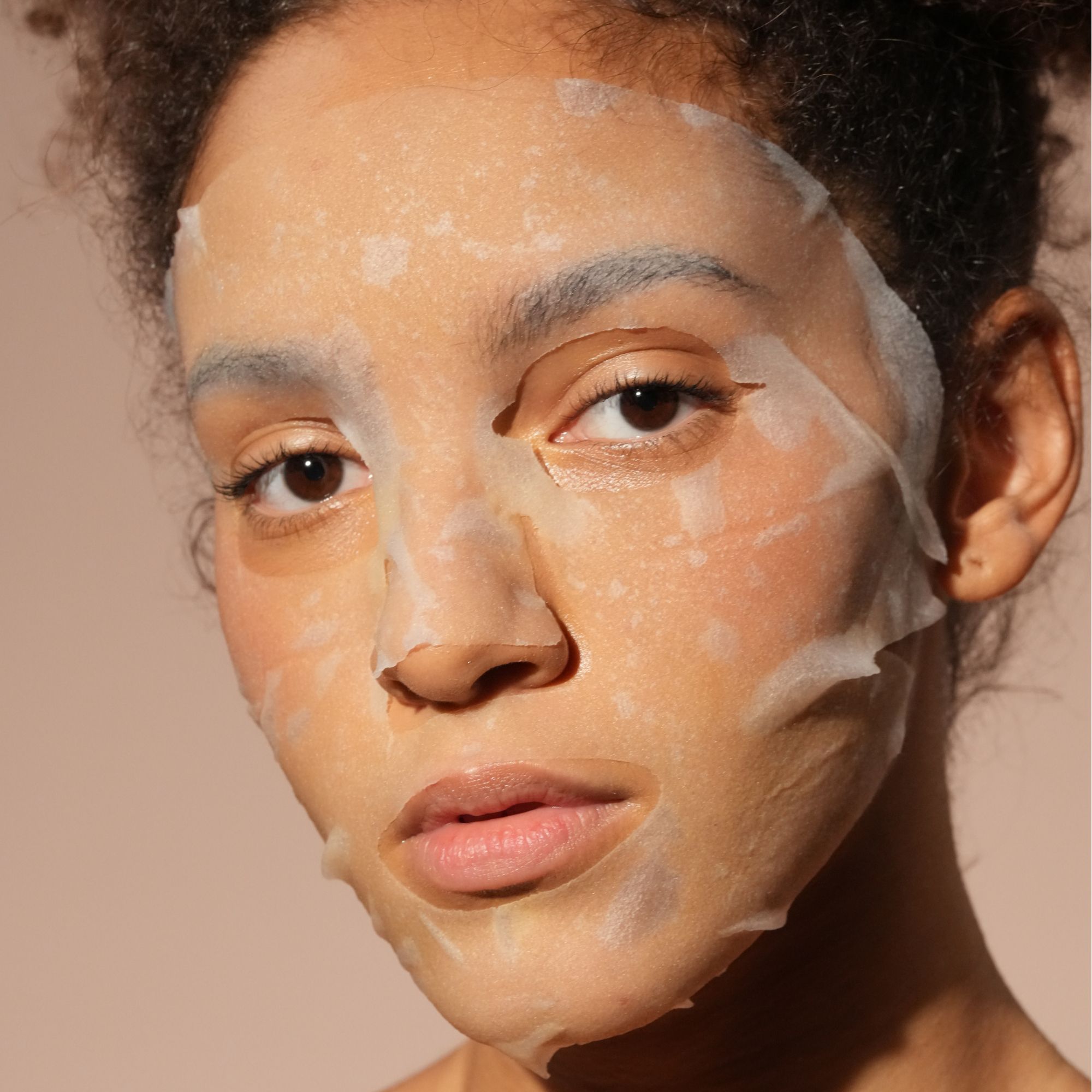 Femme portant un masque facial hydratant en tissu à base de collagène.