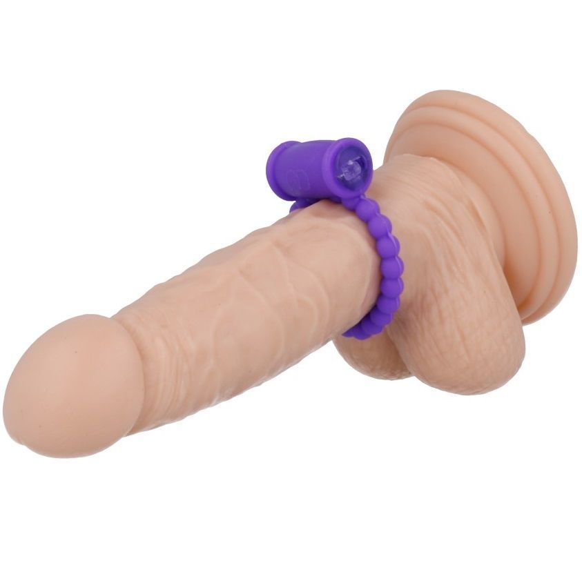 Anneau vibrant violet avec perles fixé sur un modèle de pénis. Embout en haut.