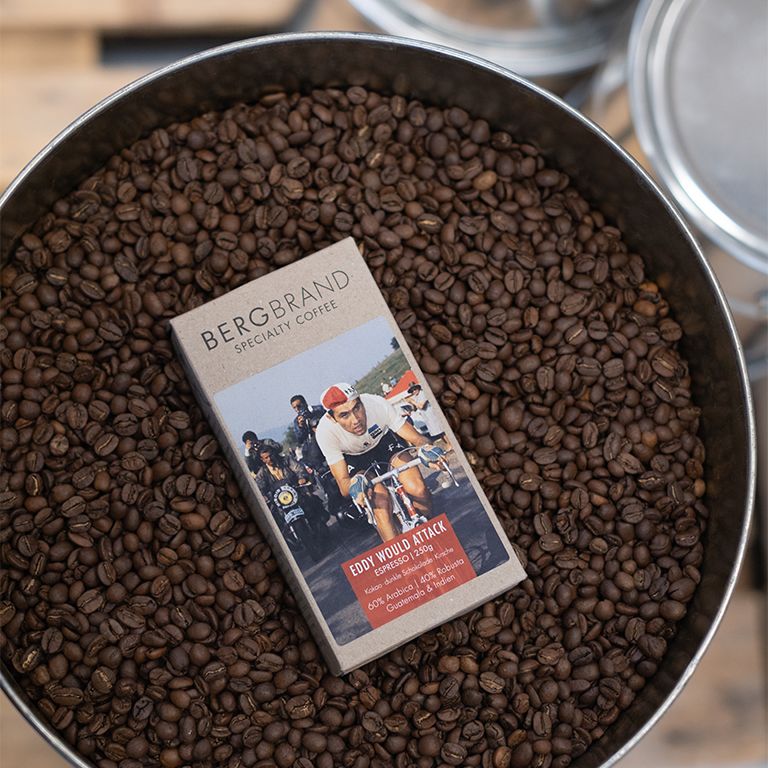 Grains de café dans un récipient métallique. Paquet avec étiquette Eddy World Attack dans les grains.